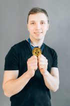 man in black crew neck short holding a gold medal