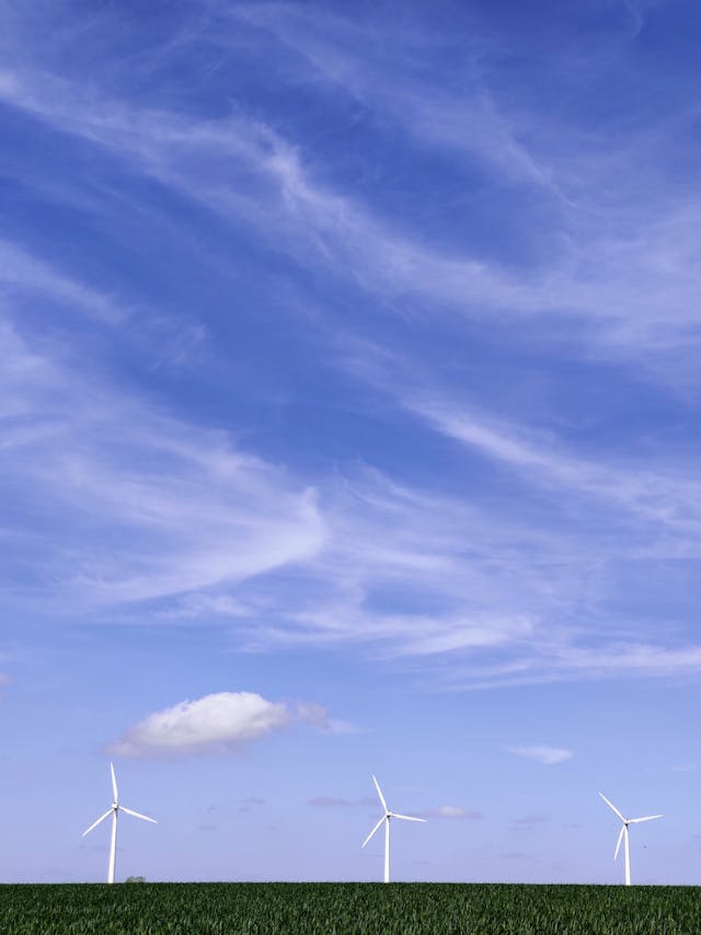 white wind turbines under blue sky and white clouds